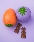 Une carotte orange et une autre mauve en chocolat accompagnées de deux lapins en chocolat.