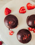 Des petits gonflés fraises et thé des bois sur un plateau comme présentoir entourés de morceaux de fraises.