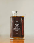 Une bouteille de sirop d'érable pur foncé de l'entreprise Trace - Érable & Territoire.