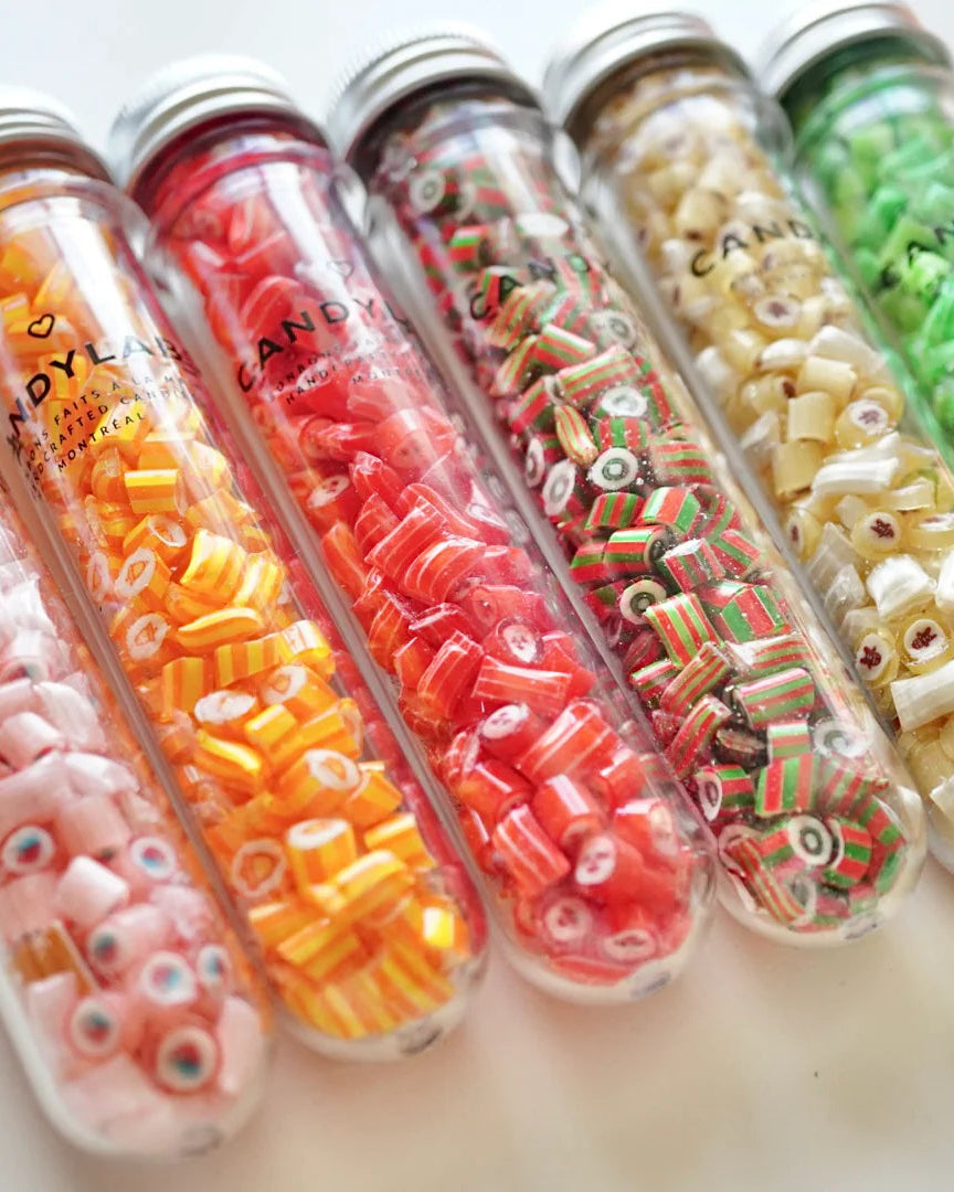 Des tubes de bonbons à l'effigie de Noël de Candy Labs côte-à-côte sur une table.