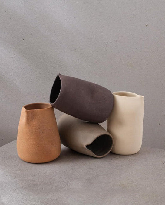 Des carafes de couleurs différentes de l'entreprise Dompierre, sont sur une table un peu pèle-mèle.