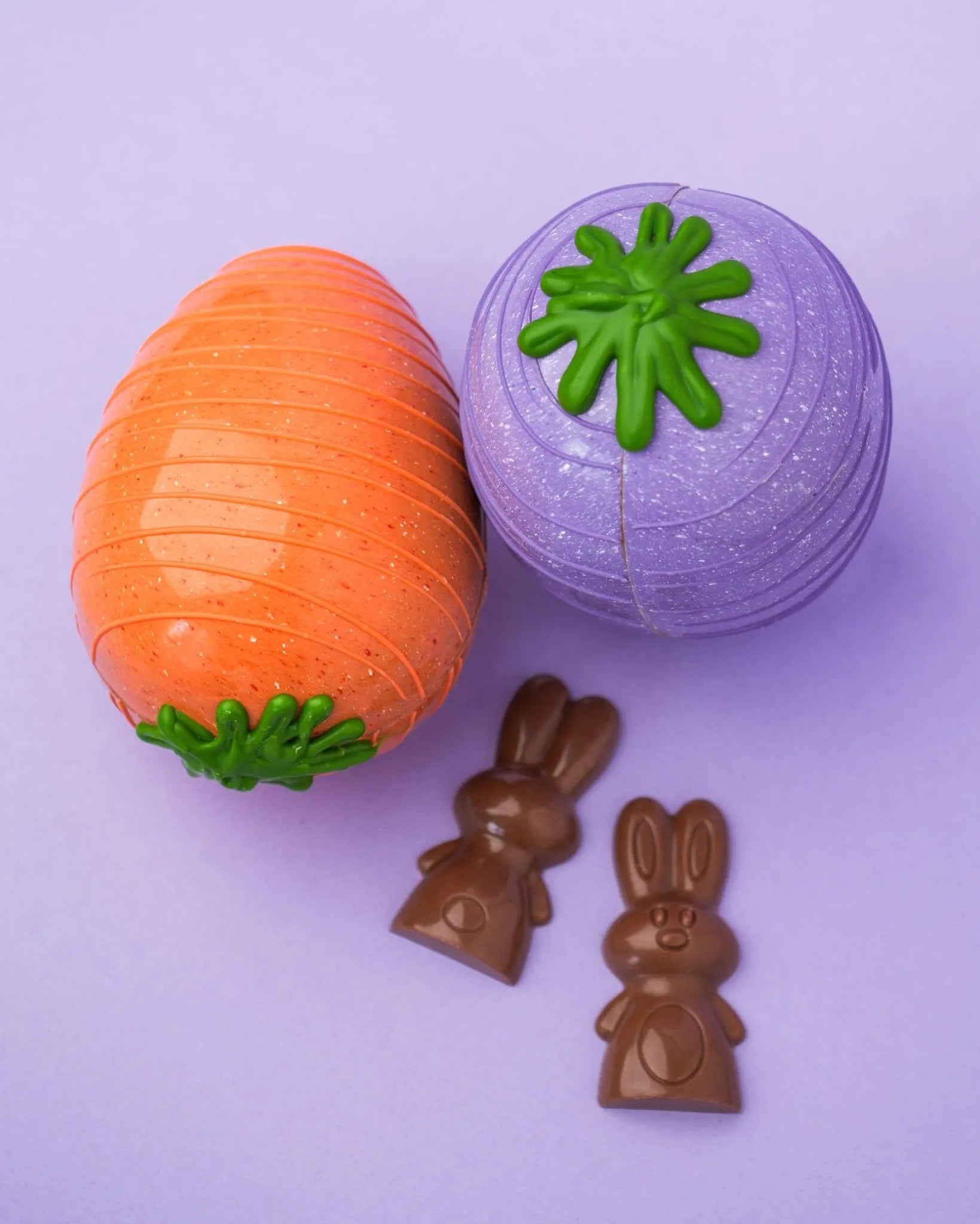Une carotte orange et une autre mauve en chocolat accompagnées de deux lapins en chocolat.