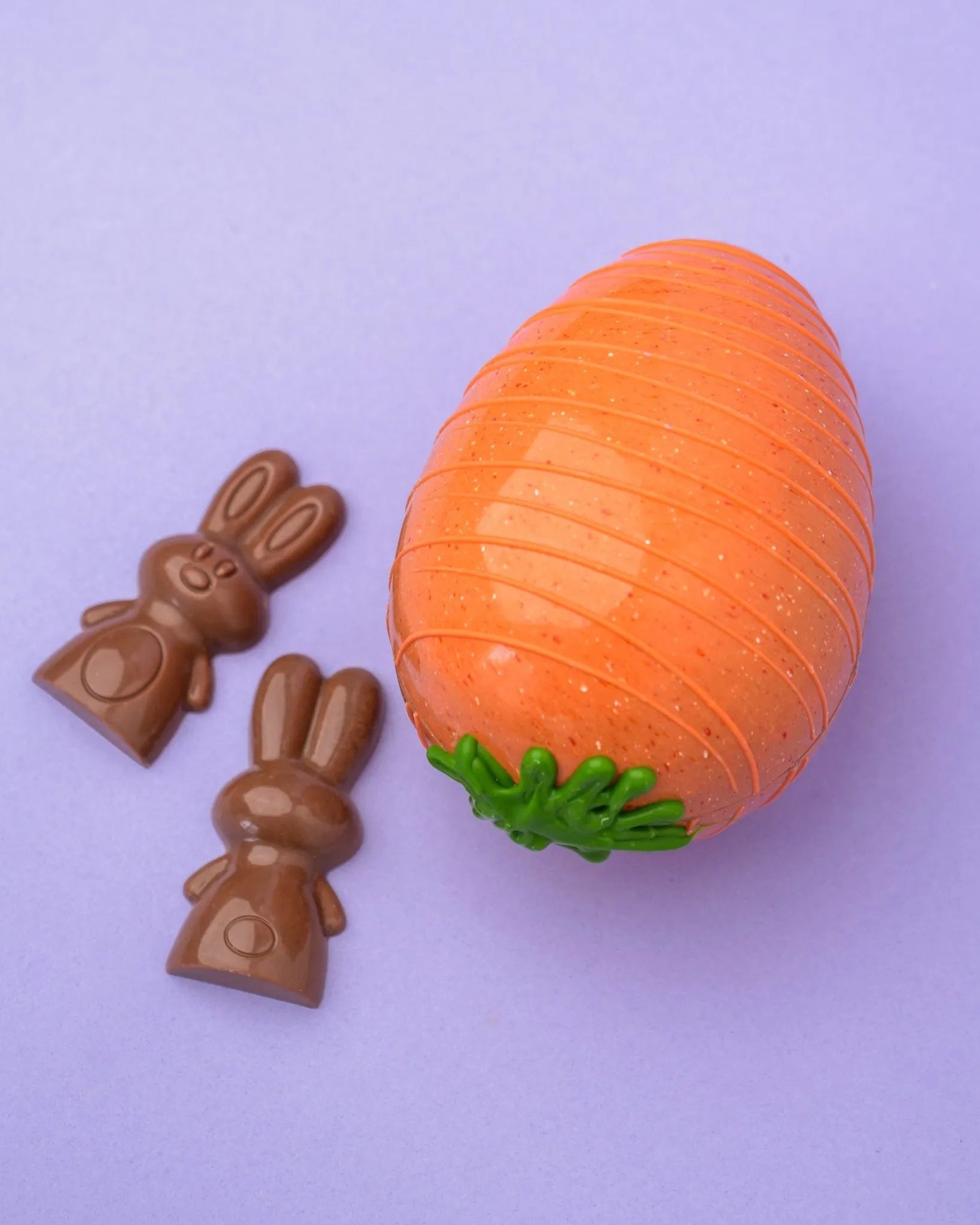 Une carotte en chocolat accompagnée de deux lapins en chocolat.