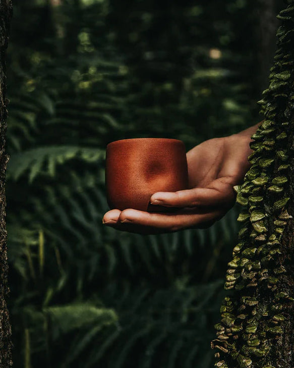 Un gobelet de couleur terra cotta de l'entreprise dompierre dans un décor forestier.