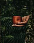 Un gobelet de couleur terra cotta de l'entreprise dompierre dans un décor forestier.