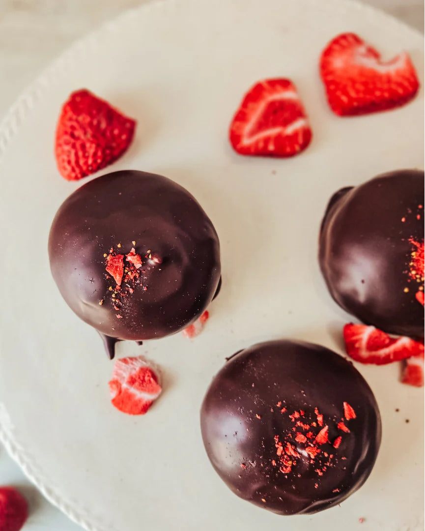 Des petits gonflés fraises et thé des bois sur un plateau comme présentoir entourés de morceaux de fraises.
