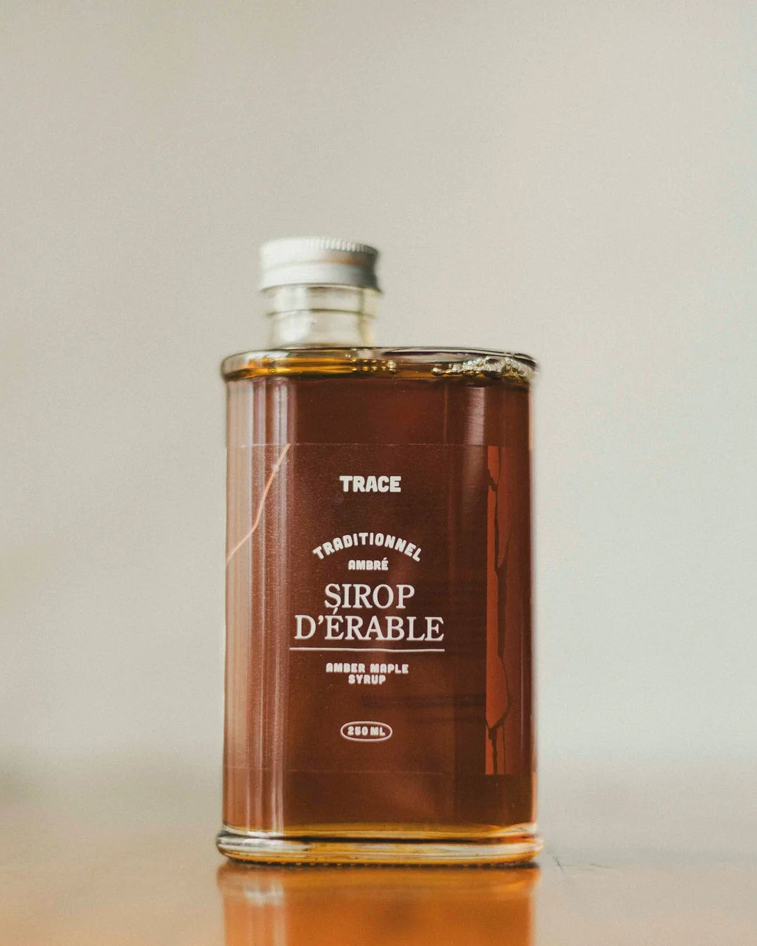 Une bouteille de sirop d'érable pur ambré de l'entreprise Trace - Érable & Territoire.